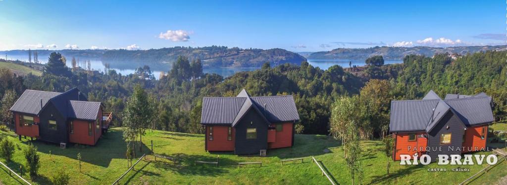 a group of cottages on a hill with a lake at Parque Natural Rio Bravo Lodge in Castro