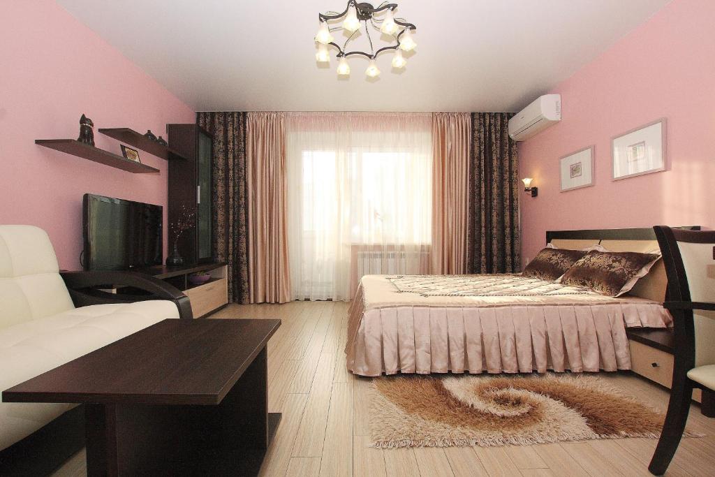 1 dormitorio con paredes rosas, 1 cama y 1 mesa en Alt-Otel Apartments, en Chelyabinsk