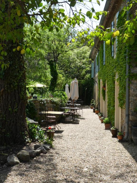 a walkway with tables and chairs in a garden at Gîte Eloi Merle in Olonzac