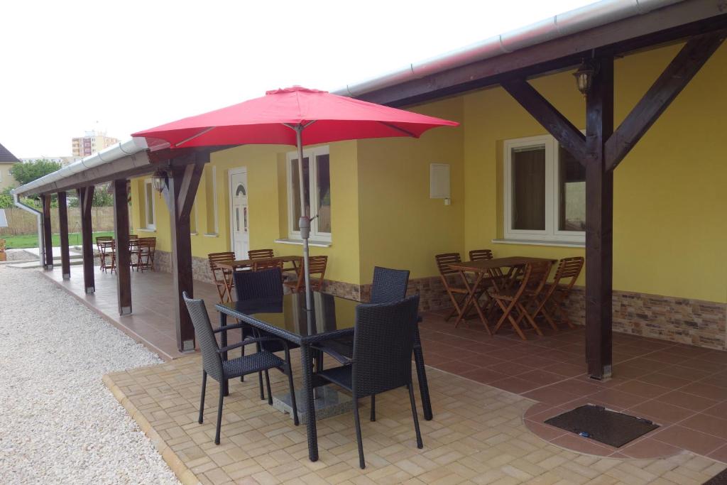 eine Terrasse mit einem Tisch, Stühlen und einem roten Regenschirm in der Unterkunft La Familia in Štúrovo
