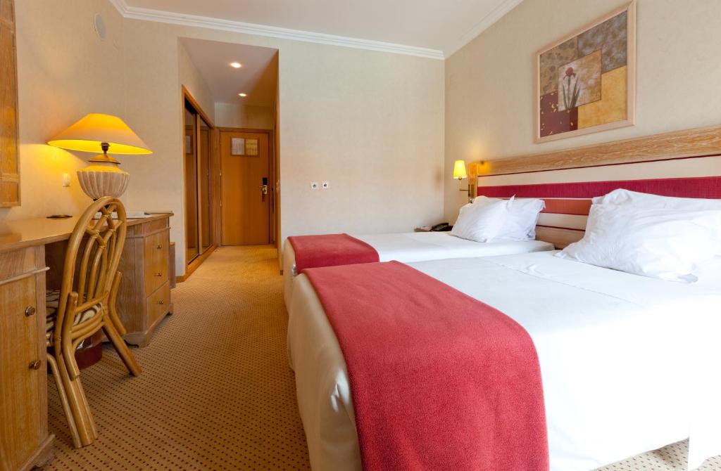 a hotel room with two beds and a desk at Riviera Hotel in Carcavelos