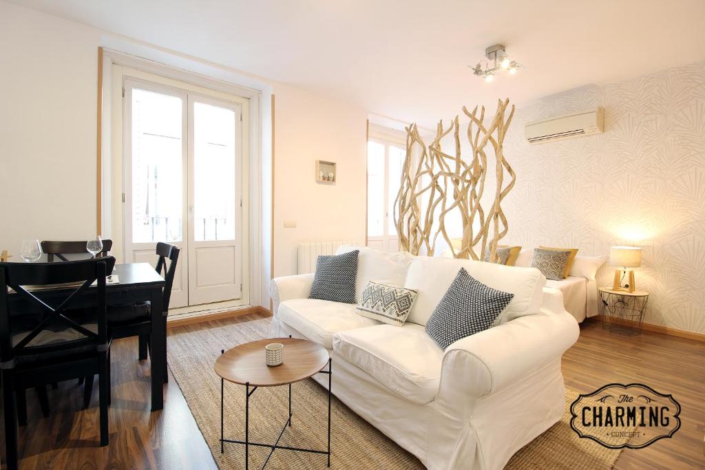 sala de estar con sofá blanco y piano en Huertas Apartment - Estancias temporales, en Madrid