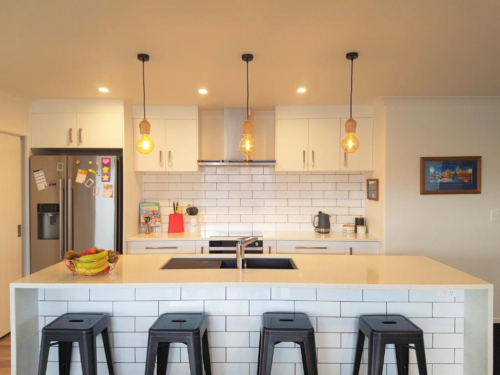 a kitchen with a counter with stools in it at House In The Heights in Taupo