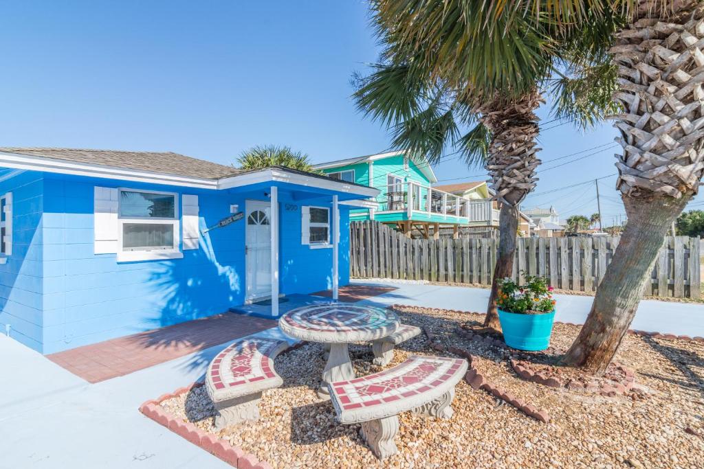 a blue house with two benches and a palm tree at Villa Paradise, Pet Friendly in Panama City Beach