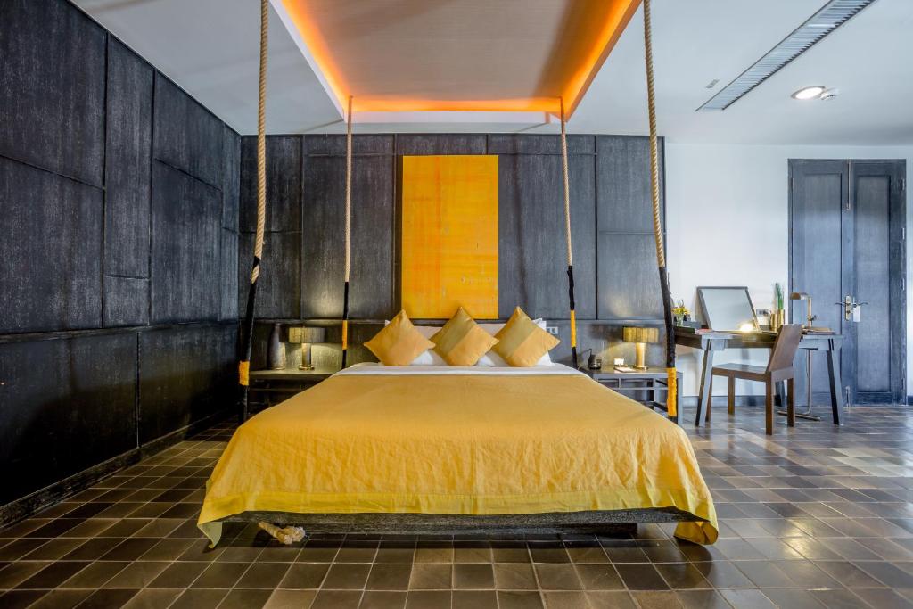 a bedroom with a large bed with a yellow bedspread at Aruntara Riverside Boutique Hotel -SHA Extra Plus in Chiang Mai