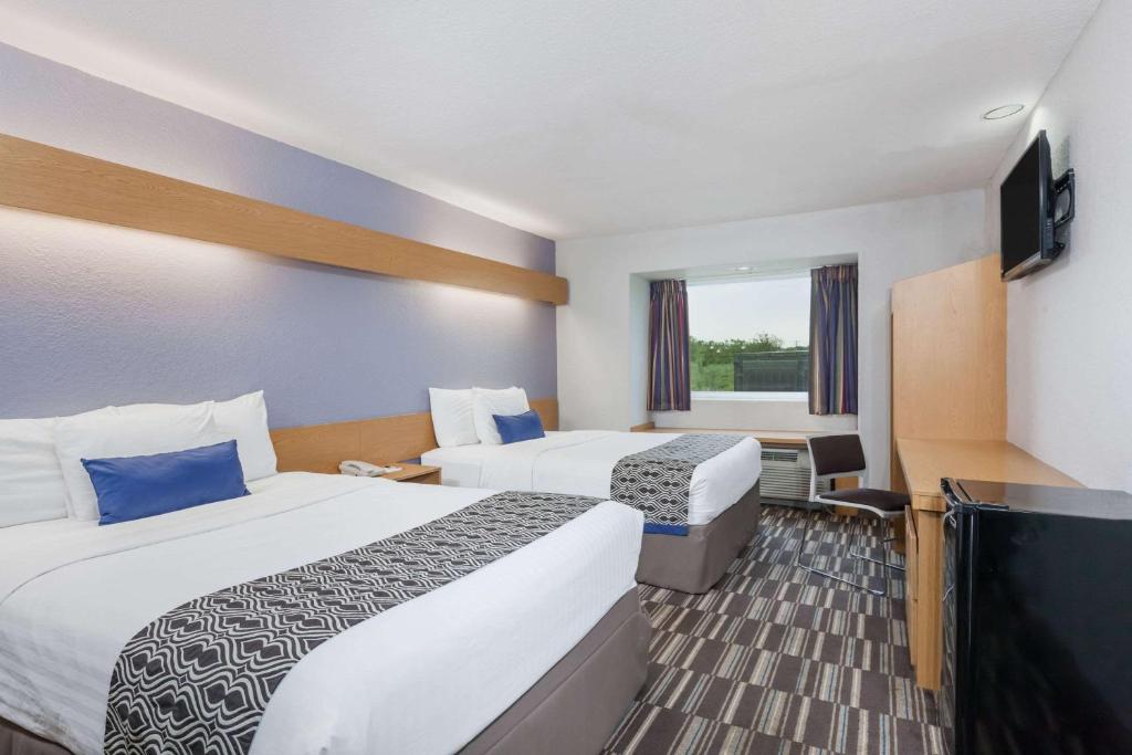 a hotel room with two beds and a flat screen tv at Microtel Inn & Suites by Wyndham Ardmore in Ardmore
