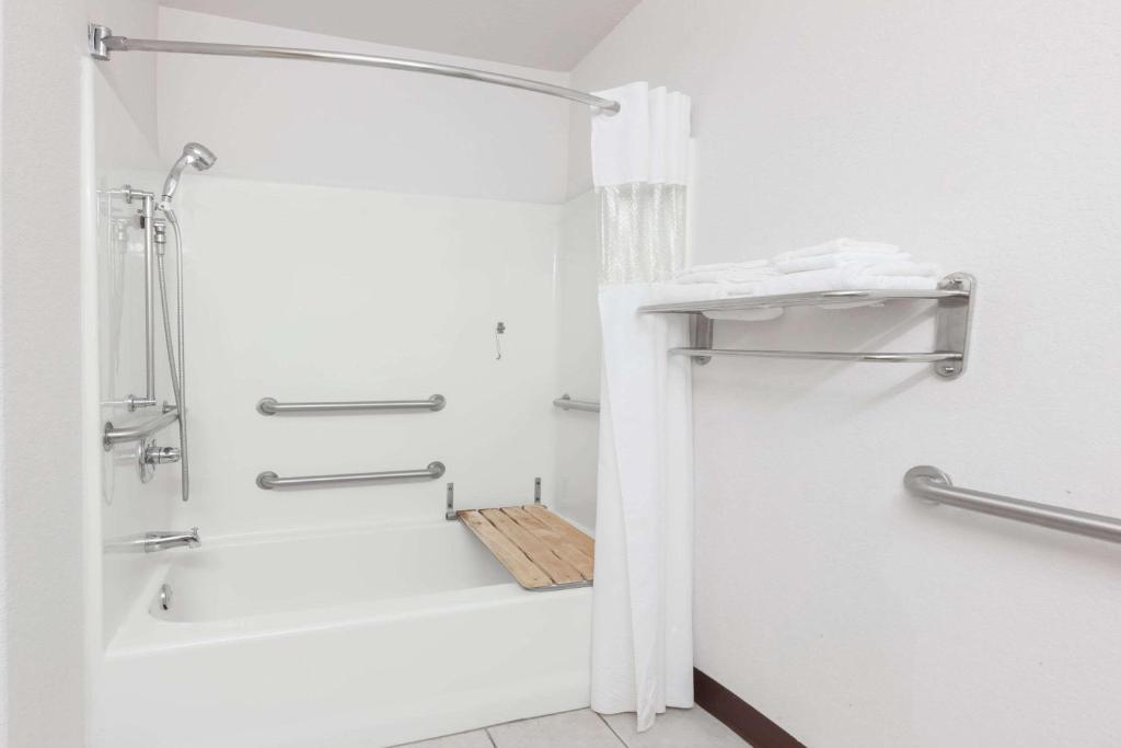 a white bathroom with a shower and a tub at Microtel Inn & Suites by Wyndham Ardmore in Ardmore