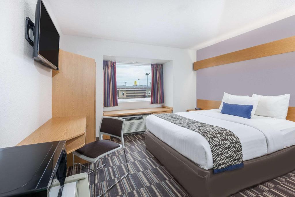 a hotel room with a bed and a flat screen tv at Microtel Inn & Suites by Wyndham Ardmore in Ardmore