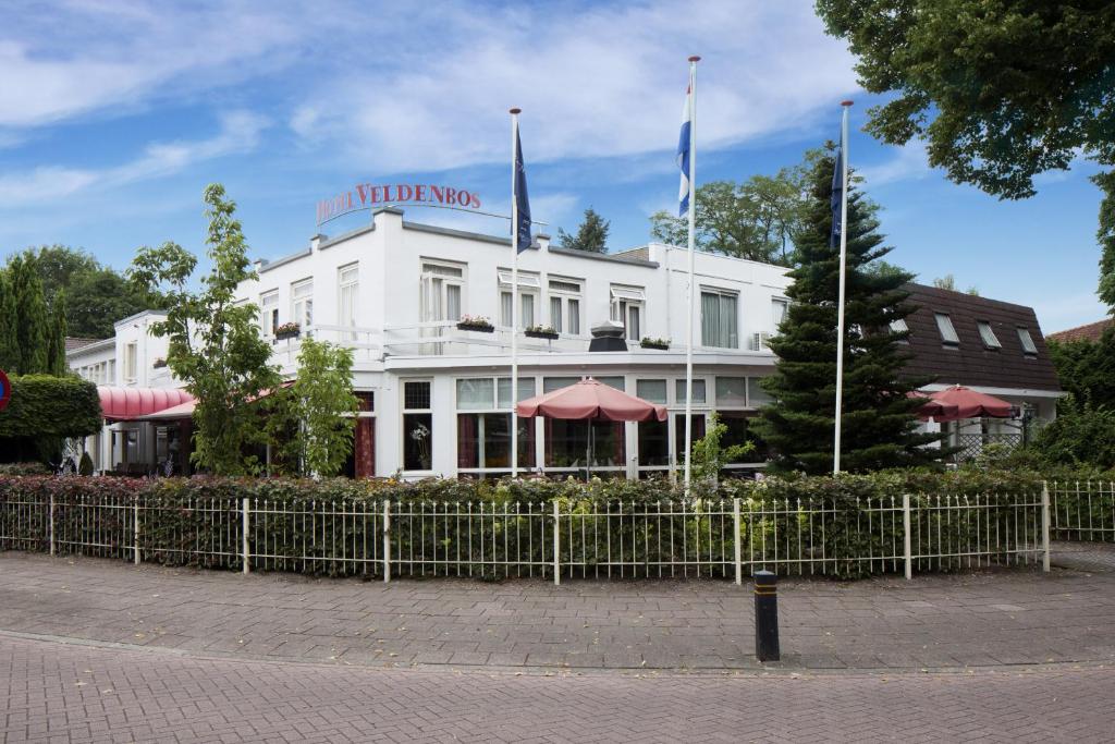 um edifício branco com duas bandeiras em cima em Fletcher Hotel Restaurant Veldenbos em Nunspeet