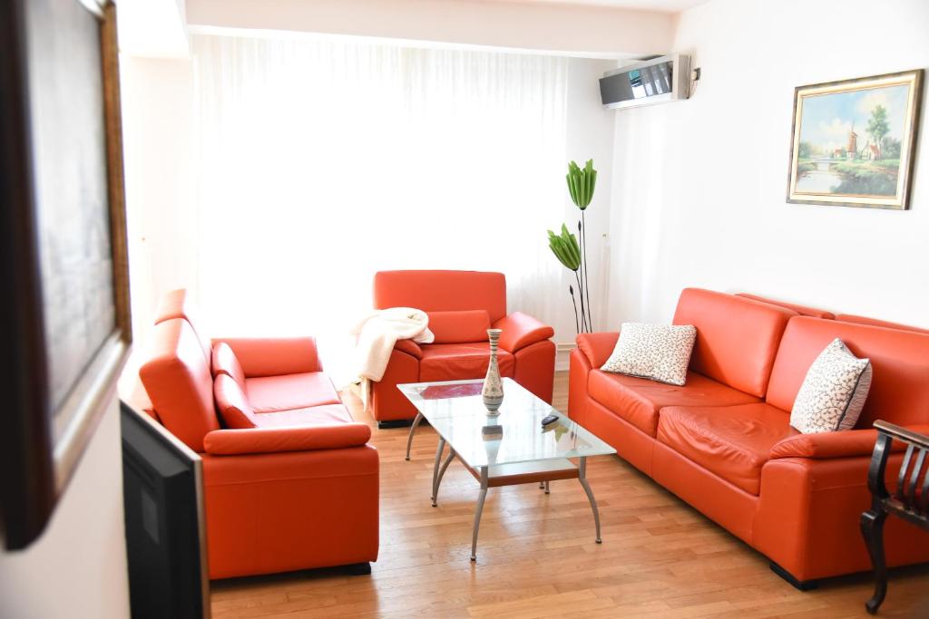 a living room with two orange couches and a table at 3 Bedroom Home with Parking Garage in The Heart of Skopje in Skopje