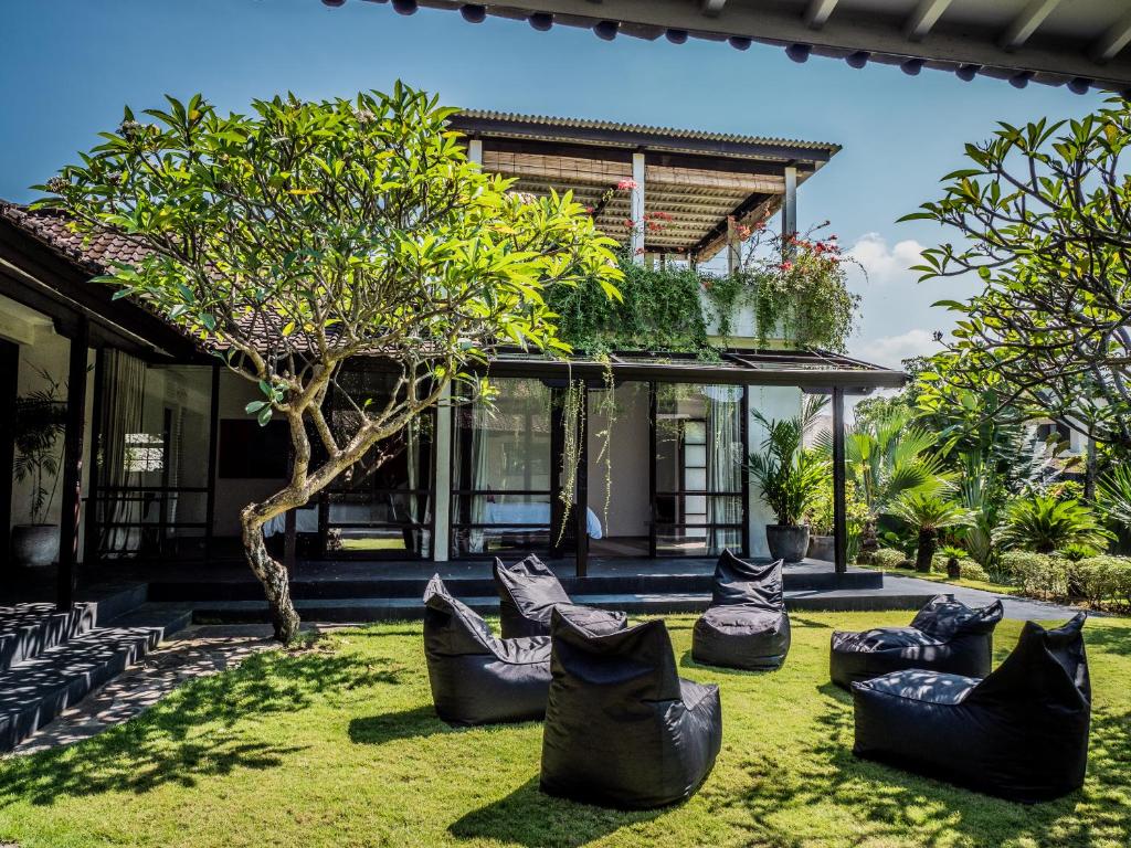 a garden with black chairs in front of a house at Holiday beautiful Villa 4 Bedroom Garden View Canggu in Canggu