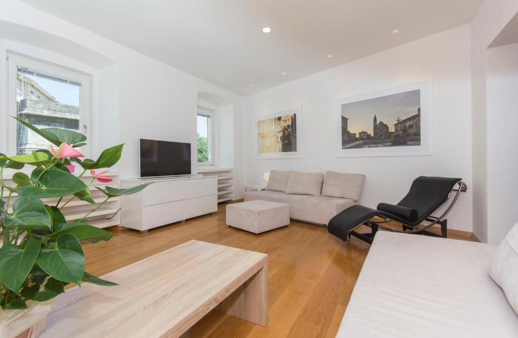 a white living room with a couch and a tv at Appartment in center with parking in Pula