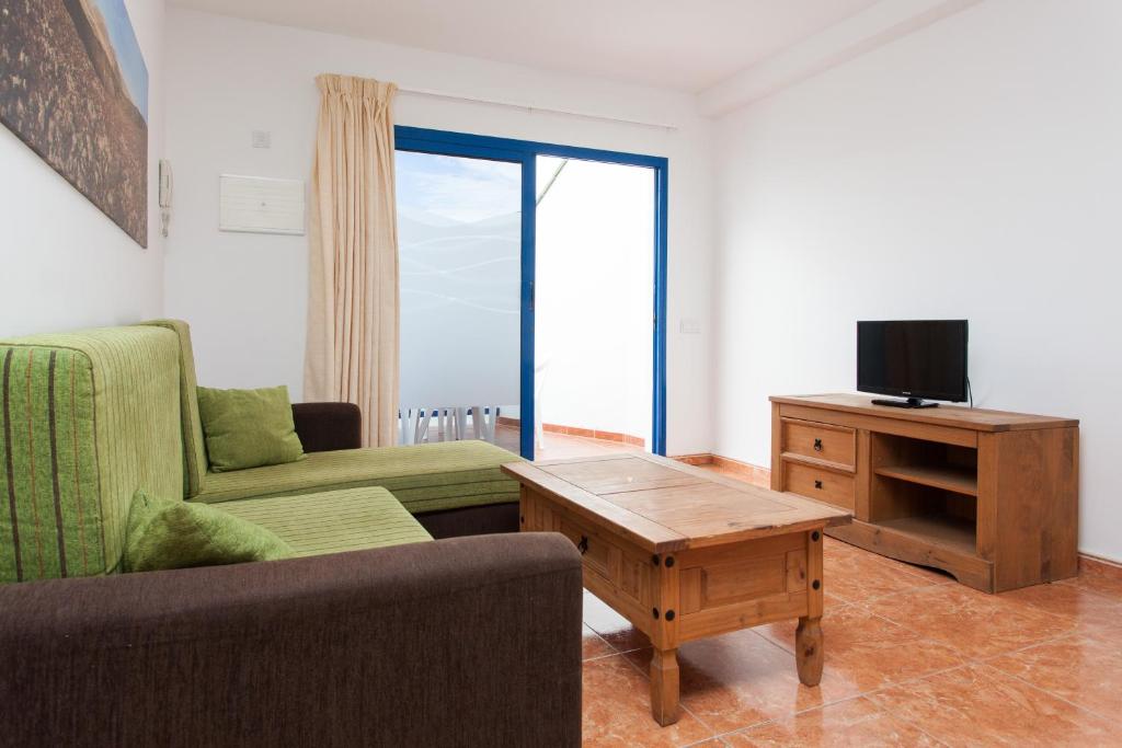 a living room with a couch and a tv and a table at TAO El Cotillo in El Cotillo