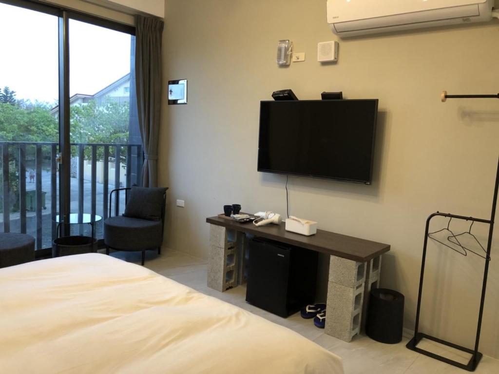 a hotel room with a bed and a flat screen tv at Kenting Peninsula Inn in Kenting