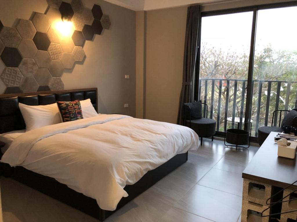 a bedroom with a large bed and a balcony at Kenting Peninsula Inn in Kenting