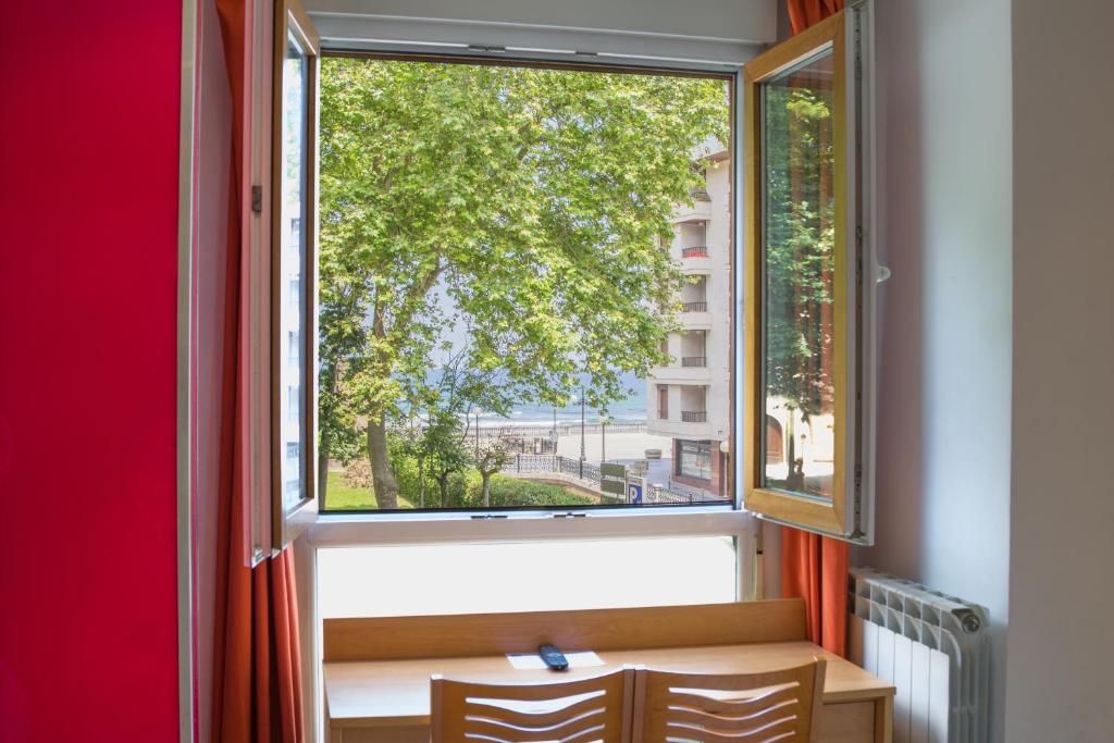 a window with a view of a tree at Ekia Pentsioa in Zarautz