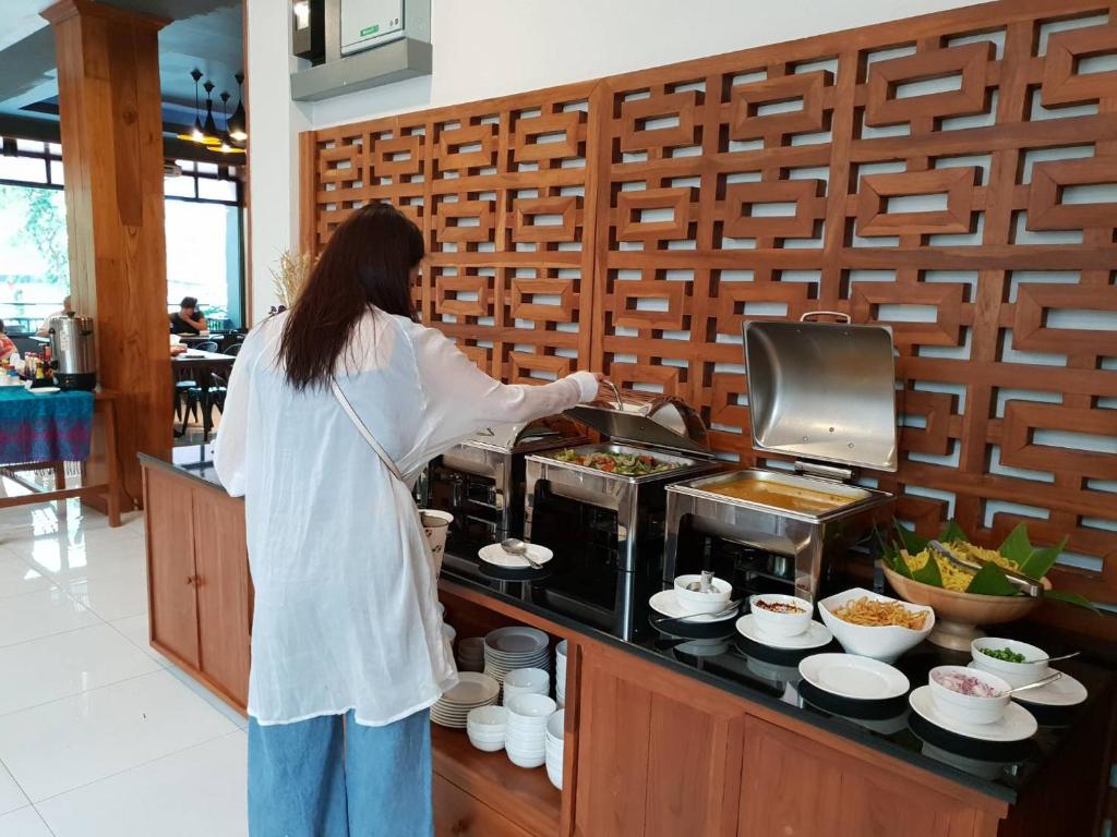A breakfast buffet station with hot dishes, bowls and serving utensils beside a decorative wood screen.