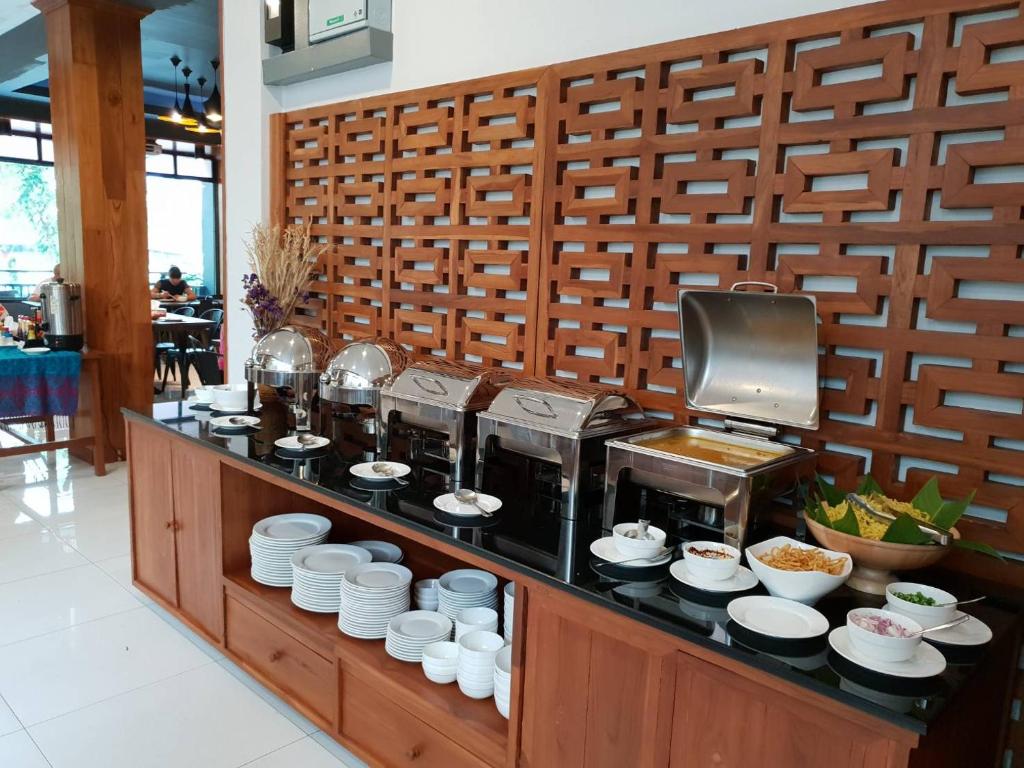 A neatly arranged buffet counter with covered hot dishes, plates, bowls and toppings.