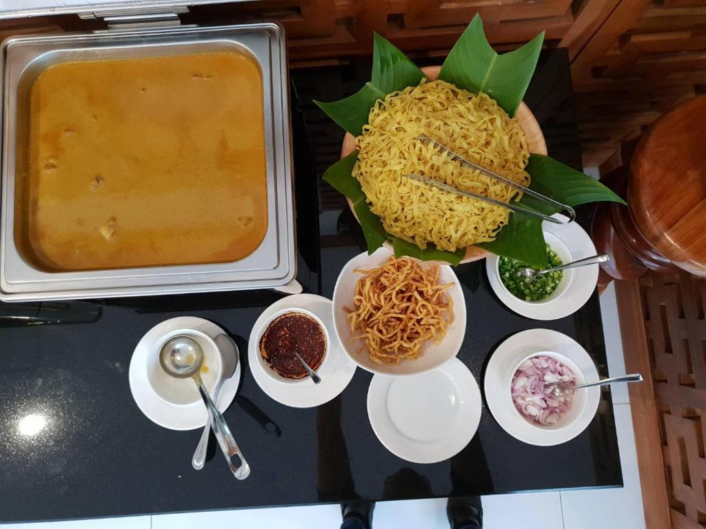 A close-up of noodle dishes with curry or sauce, herbs and sliced accompaniments at the buffet.