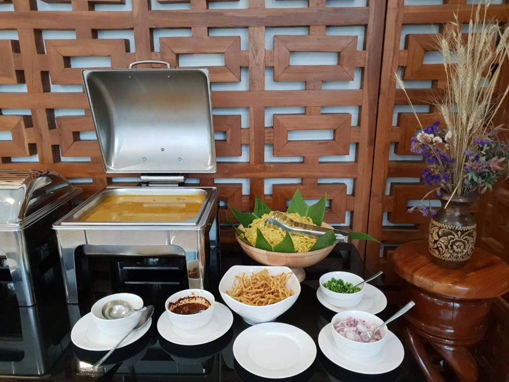 A buffet station with hot food, noodles, garnishes and bowls beside a tabletop grill.