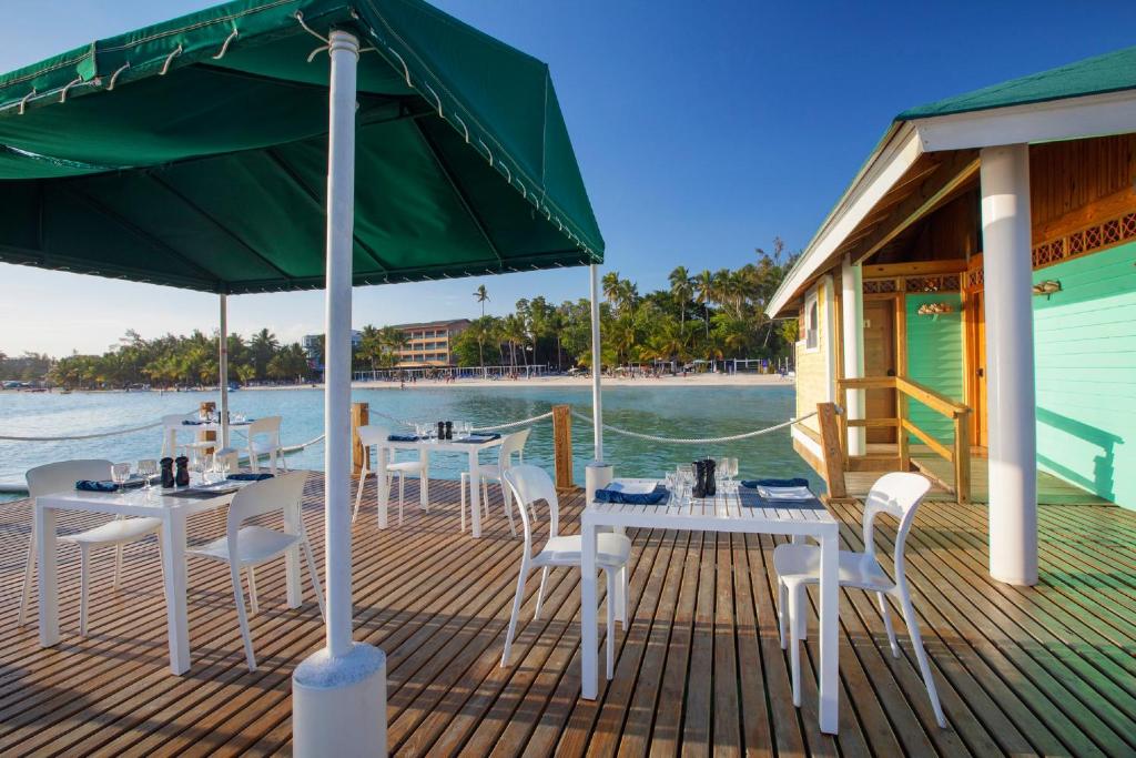 a deck with tables and chairs and a green umbrella at Hotel whala!boca chica - All Inclusive in Boca Chica