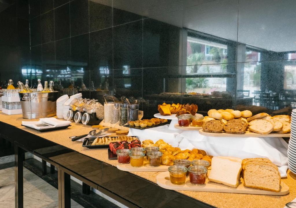 a buffet with many different types of bread and pastries at Topazio Vibe Beach Hotel & Apartments - Adults Friendly in Albufeira