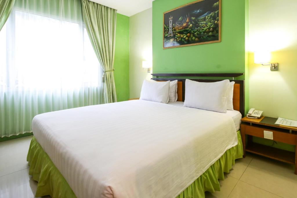 a bedroom with a large bed in a green room at Mariani International Hotel in Padang