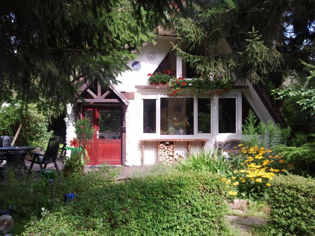 una puerta roja en una casa blanca con flores en Finnhütte Canow, en Canow