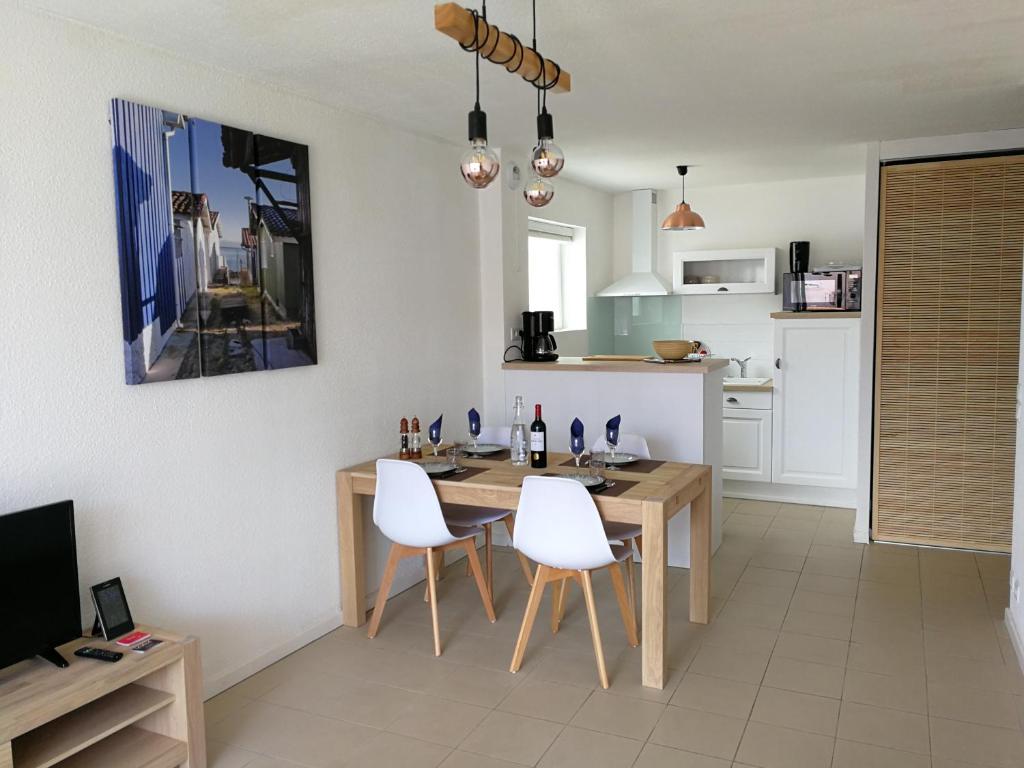 a kitchen with a wooden table and white chairs at Appt. Bella Vita - Andernos les Bains, au cœur du Bassin d'Arcachon in Andernos-les-Bains