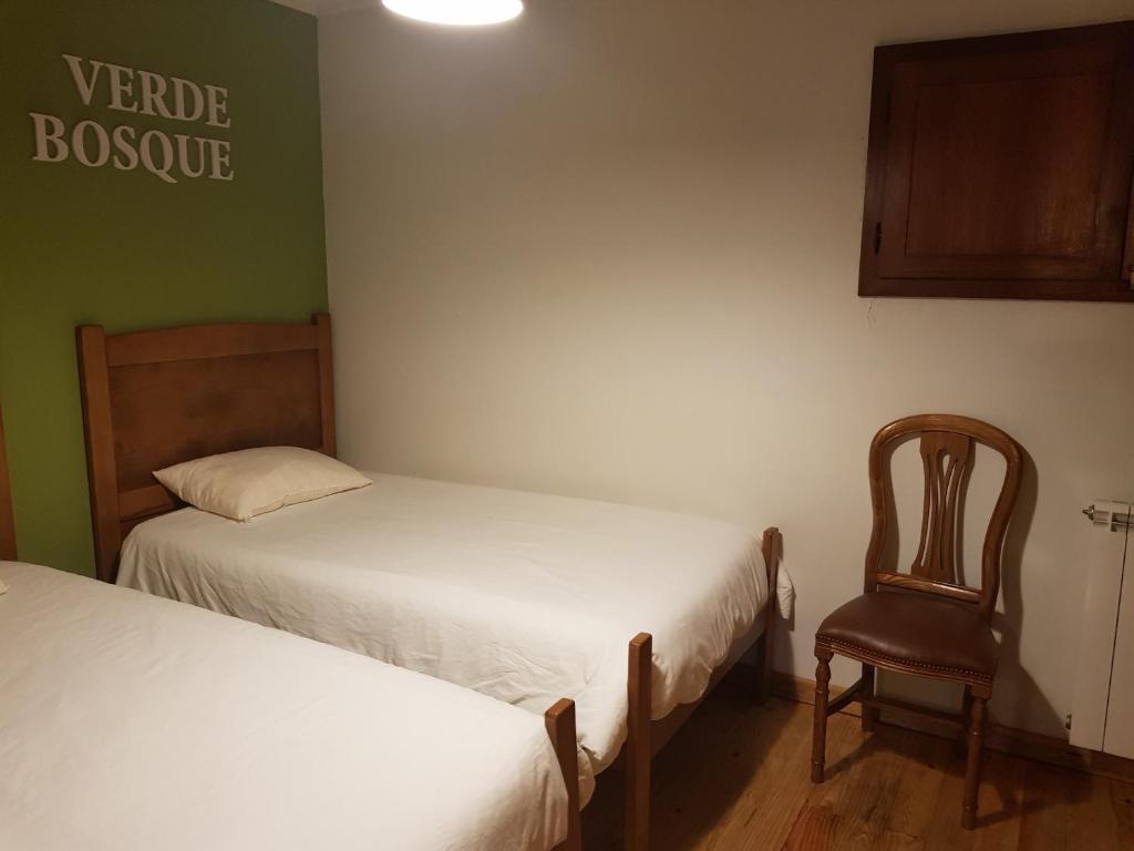 a small room with two beds and a chair at Abrigo da Geira House in Campo do Gerês