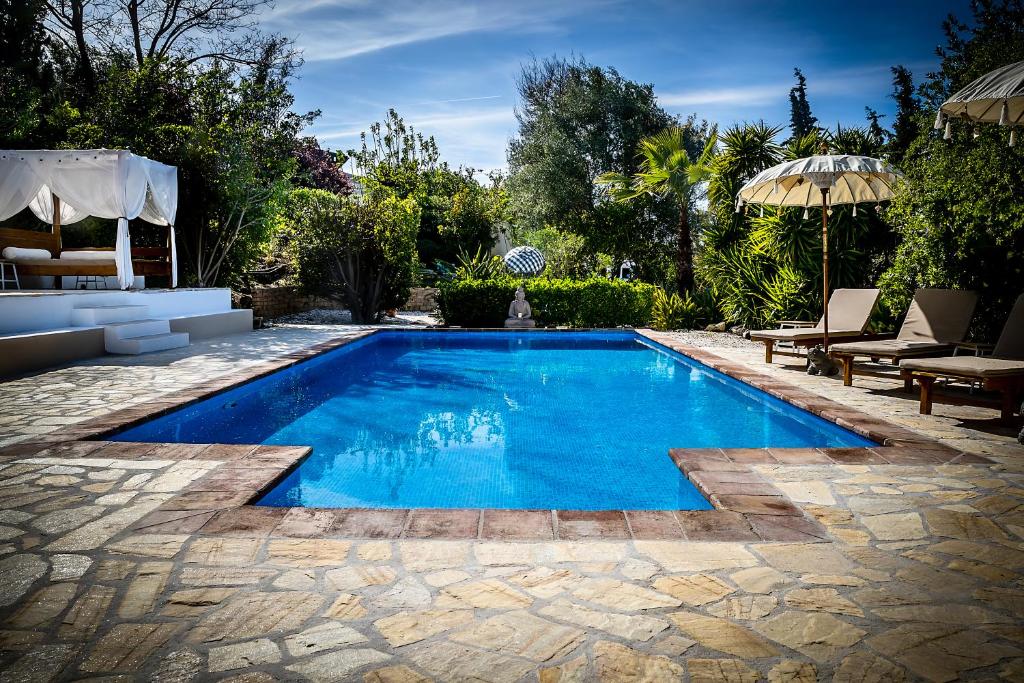 a swimming pool in a yard with chairs and an umbrella at Casa Baliza, adults only in Alhaurín el Grande