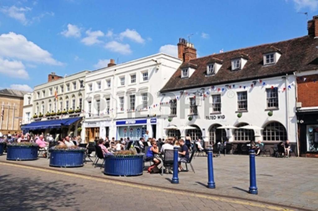 um grupo de pessoas sentadas em cadeiras em uma rua da cidade em Warwick Market Place Apartment em Warwick