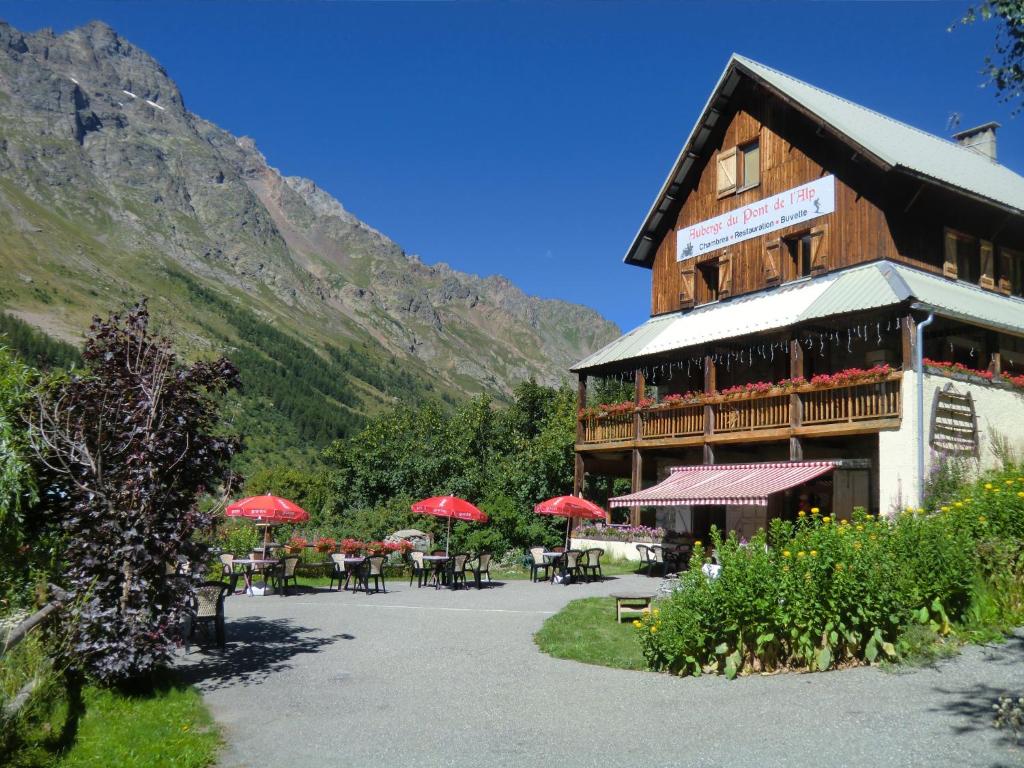 a building with tables and red umbrellas in front of it at Auberge du Pont de l'Alp in Le Monêtier-les-Bains