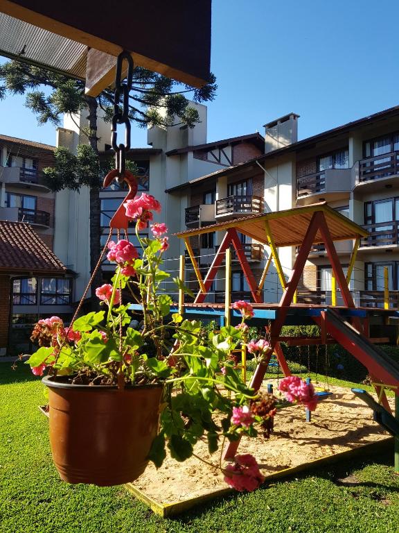 a garden with a play structure and flowers in a yard at Residencial Pousada do Serrano in Gramado