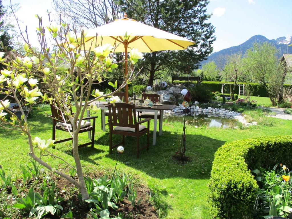 einen Tisch und Stühle unter einem Sonnenschirm in einem Garten in der Unterkunft Ferienwohnung Goller in Lenggries