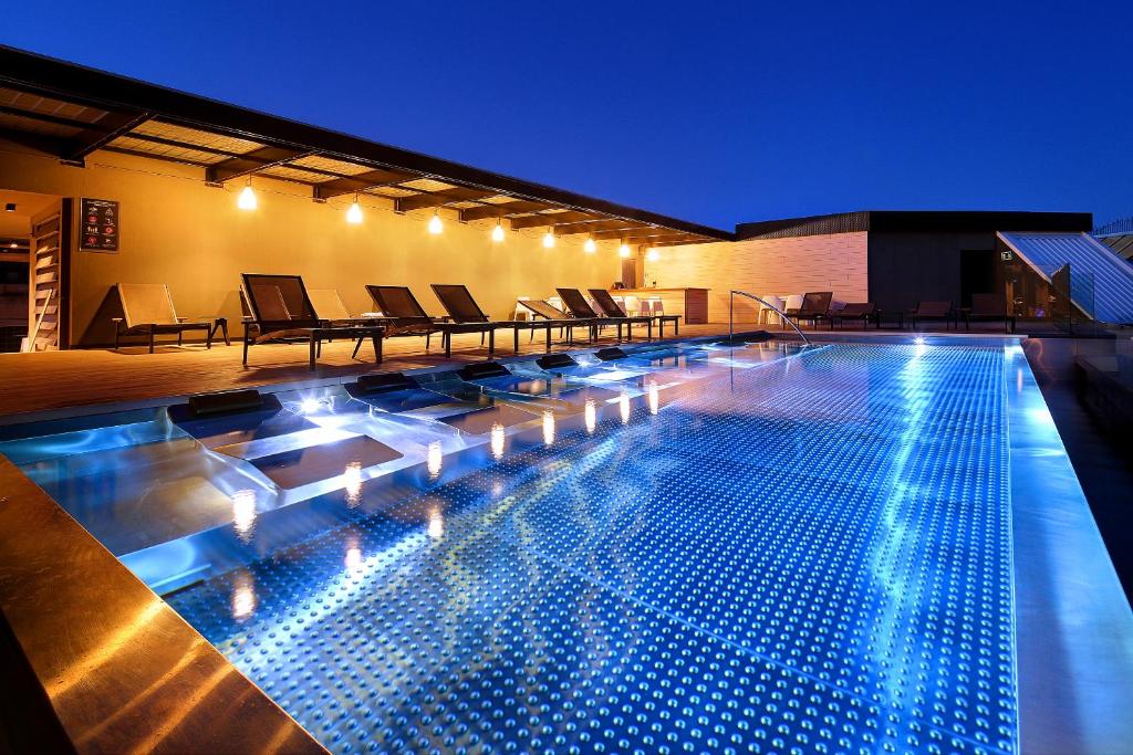 una grande piscina con luci in cima a un edificio di Olivia Balmes Hotel a Barcellona