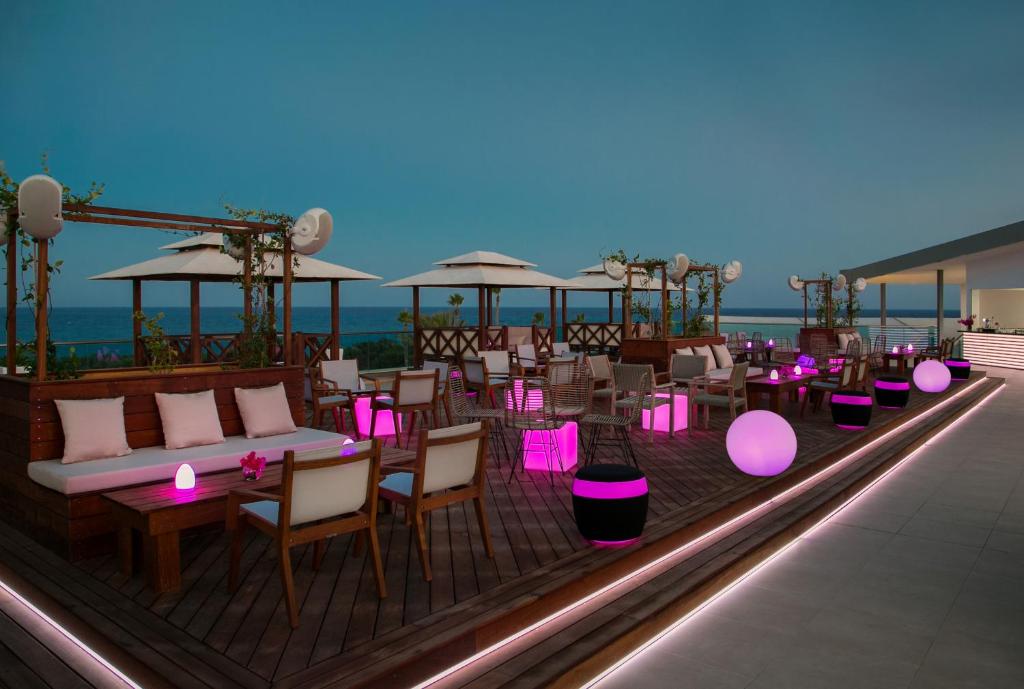 a rooftop patio with tables and chairs and purple lights at Asterias Beach Hotel in Ayia Napa