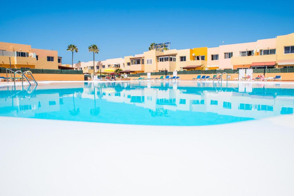 una piscina vacía con edificios de fondo en Apartment Delfines Sand Corralejo By Holidays Home, en Corralejo