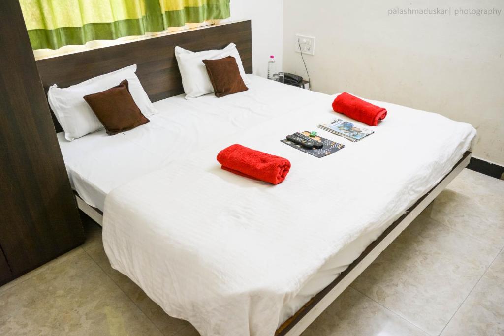 ein großes weißes Bett mit roten Kissen darauf in der Unterkunft Hotel Bholenath Palace in Ujjain