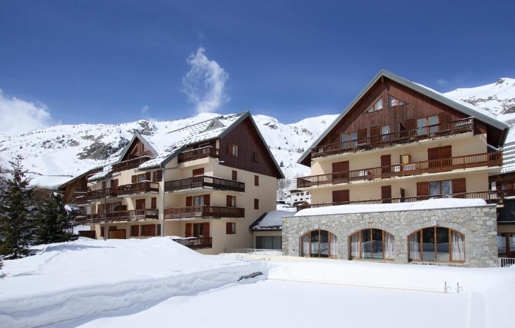 un grand bâtiment dans la neige avec des montagnes en arrière-plan dans l'établissement Résidence Odalys Les Sybelles, à Saint-Sorlin-dʼArves