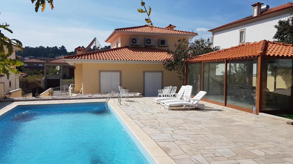 a swimming pool with chairs and a house at Afonso's House Alpendurada in Memorial