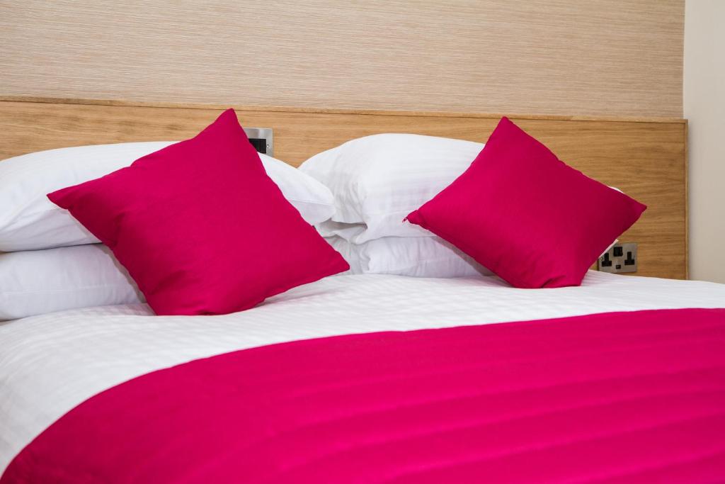 a bed with two pink pillows on top of it at Hill Park Hotel in Rosyth