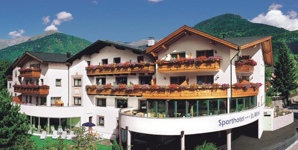 ein Gebäude mit Blumen auf den Balkonen in der Unterkunft Sporthotel St. Michael in Mals im Vinschgau