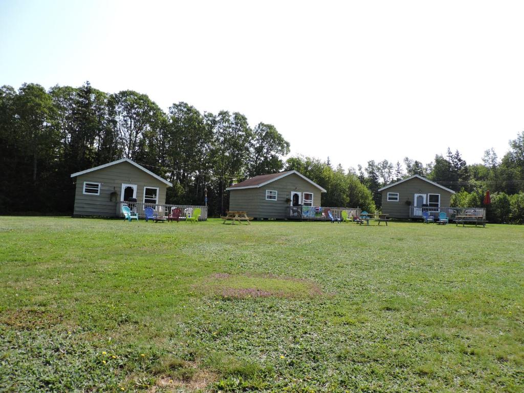 un groupe de maisons dans un champ d'herbe dans l'établissement Centennial Cottages, à Brackley Beach