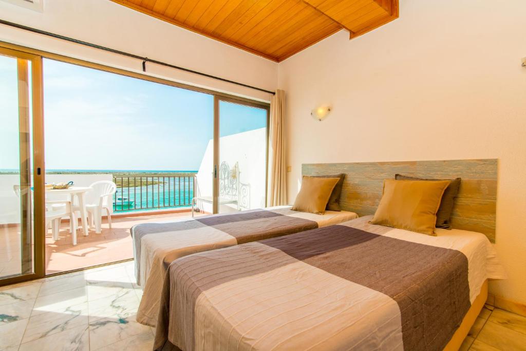 two beds in a bedroom with a view of the ocean at Cabanas Ria Sea View By Algartur in Cabanas de Tavira