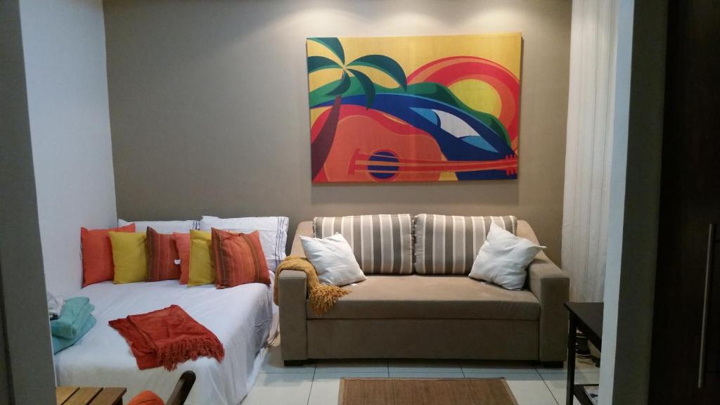 sala de estar con sofá y pintura en Charmoso Loft Studio para temporada - Recreio - Barra - RJ, en Río de Janeiro