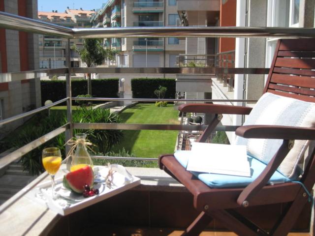 een balkon met een stoel en een tafel met wijnglazen bij Residencial Progreso Sanxenxo in Sanxenxo