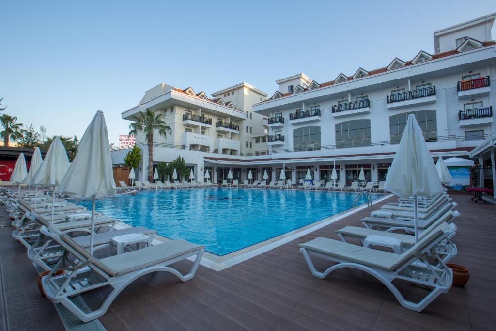 uma piscina com espreguiçadeiras e guarda-sóis em frente a um hotel em Side Aquamarin Resort & Spa em Side