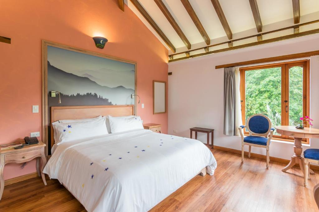 ein Schlafzimmer mit einem großen Bett und einem Schreibtisch in der Unterkunft La Casa Del Arbol Hotel Boutique Villa de Leyva in Villa de Leyva