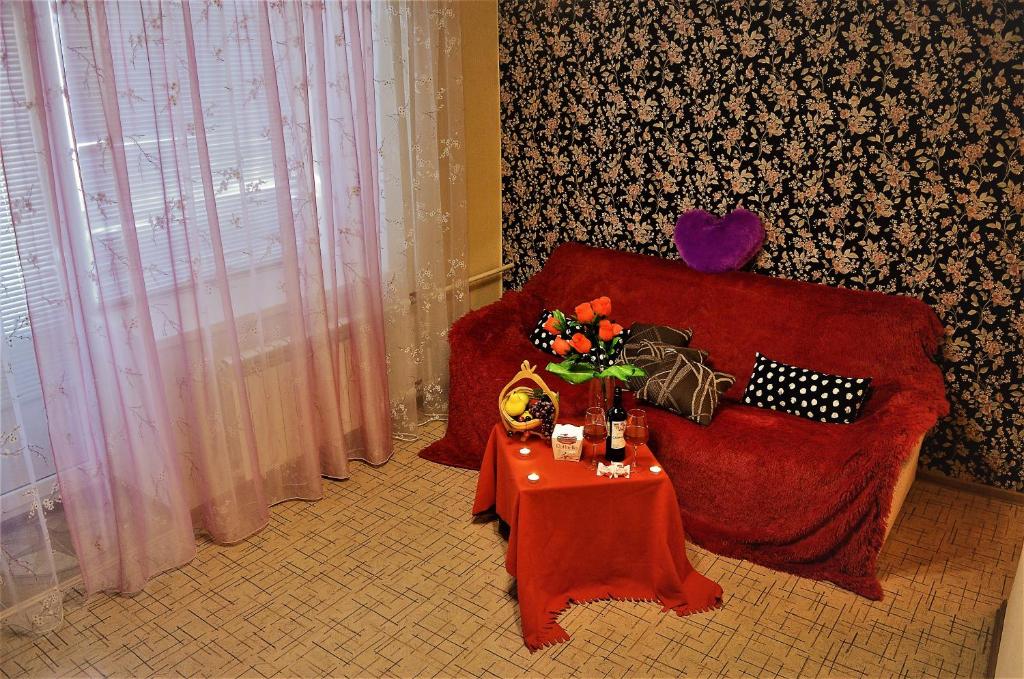 SalavatにあるКомфортの赤いソファ、花瓶付きのテーブルが備わる客室です。